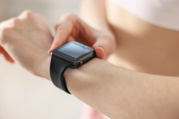 Woman checking fitness tracker during training indoors, closeup