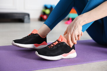 Sports injury. Young woman suffering from leg pain in fitness studio, closeup