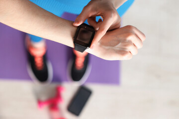 Woman checking fitness tracker during training indoors, above view