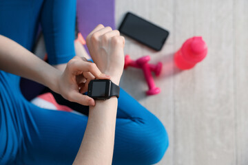 Woman checking fitness tracker during training indoors, closeup