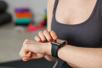 Woman checking fitness tracker during training indoors, closeup