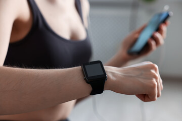 Woman checking fitness tracker during training indoors, closeup