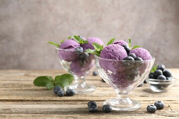 Tasty sorbet with blueberries and mint in dessert bowls on wooden table against grey background,...