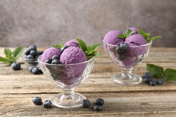 Tasty sorbet with blueberries and mint in dessert bowls on wooden table against grey background,...