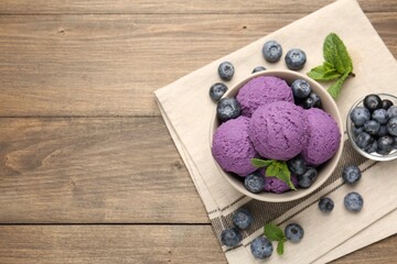 Tasty sorbet with blueberries and mint in bowl on wooden table, top view. Space for text