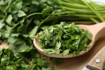 Fresh green cilantro and wooden spoon on table, closeup