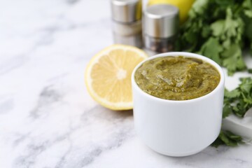 Tasty sauce with cilantro and other ingredients on white marble table, closeup. Space for text
