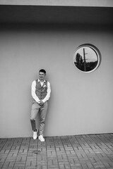 portrait of the groom in a gray suit and an orange vest