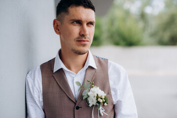portrait of the groom in a gray suit and an orange vest