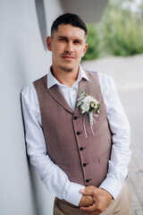 portrait of the groom in a gray suit and an orange vest