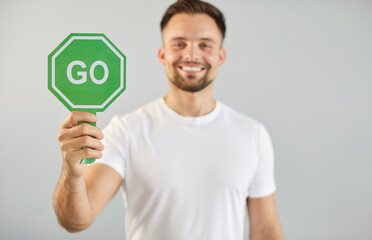 Man holding green sign with Go word to start forward movement, begin challenge or road race. Happy...