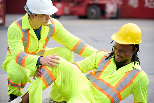 Industrial worker injured on site, his colleague providing immediate support, symbolizing workplace safety and accident response
