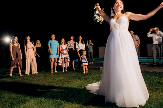 bride in a white dress throws a wedding bouquet