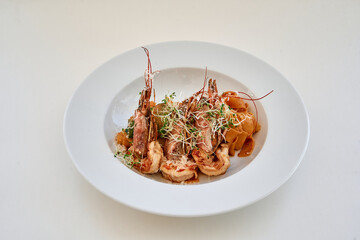 Gourmet shrimp dish with vegetables in white bowl on elegant table setting