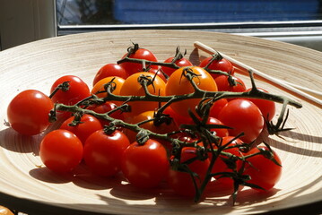 Cherry tomatoes yellow and red on branches on a bamboo plate