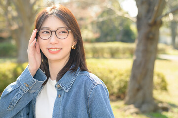 公園で微笑むメガネをかけた日本人女性