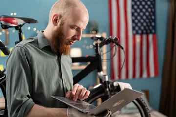 mechanic working on laptop while doing bicycle diagnostic test repairing bike at home