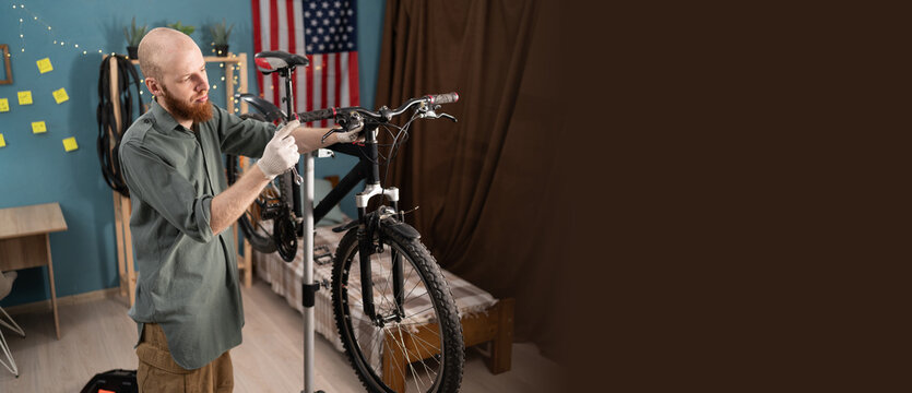 Bike maintenance and DIY repair concept. young bearded man repairing his bicycle at home. Copy space