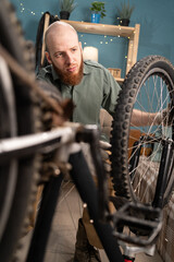 Young bearded man repairing mountain bicycle