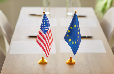 Conference room with USA and European Union flags on table with no people symbolising collaboration...