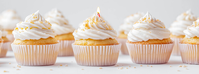 Delicious cupcakes with white frosting and a lit candle on one.