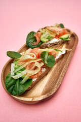Fresh avocado salmon sandwich on wooden plate with spinach fennel and cream cheese