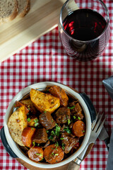 Hearty beef stew with vegetables on checkered tablecloth