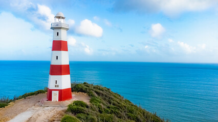 Red and White Lighthouse by the Ocean on a Sunny Day