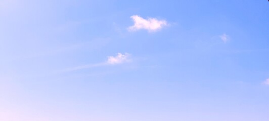 Beautiful blue sky background with fluffy white cloud formations on a clear day with warm sunshine. Clear blue sky, soft sky gradient, landscape wallpaper. Peaceful and serene atmosphere.