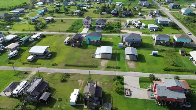 Colorful raised houses and RVs, trailers near Beach Boyt in Port Bolivar, Texas, large grassy lots and ocean views evoke relaxed coastal lifestyle blending vacation homes and storm-safe design