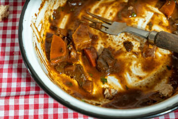 Hearty beef stew remnants on checkered tablecloth