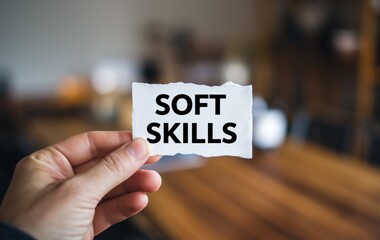 A hand holding a piece of white paper with the text soft skills