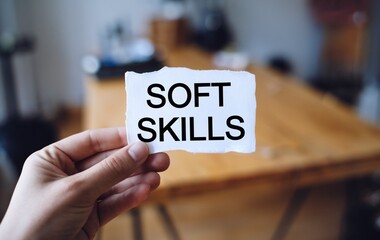 A hand holding a piece of white paper with the text soft skills