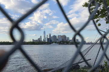 downtown manhattan new york city skyline seen through metal chain link fence from red hook brooklyn...