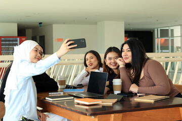 Five Asian College Student Sitting at the Table Taking Selfie Photo using Smartphone