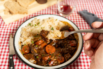 Delicious beef stew with rice on checkered tablecloth