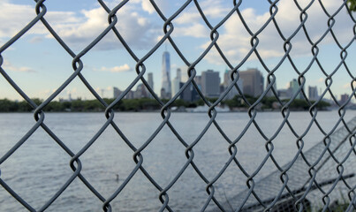 downtown manhattan new york city skyline seen through metal chain link fence from red hook brooklyn nyc usa skyscrapers tall urban buildings waterfront east river harbor travel tourism jail lockup ny