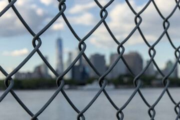 downtown manhattan new york city skyline seen through metal chain link fence from red hook brooklyn...