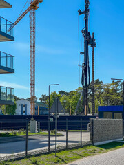 A construction site of an apartment building on the Baltic Sea in Mrzezyno, Poland with a crane and a machine for drilling holes in the ground.