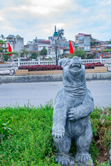 Stone Bear Statue in City: A weathered stone bear statue stands proudly against a backdrop of...