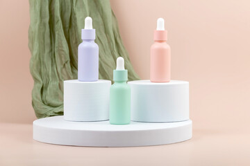 a set of bottles with an essential oil pipette on a white round podium and a green soft cloth on a...