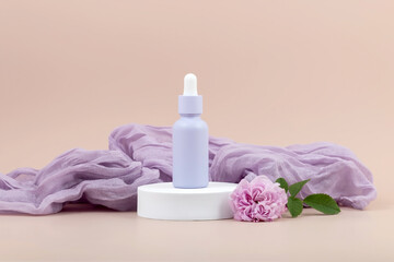 a bottle with an essential oil pipette on a white podium next to a rose flower and a soft airy...