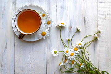Chamomile tea with fresh daisies on table. Top view of a cup of chamomile tea with fresh white...