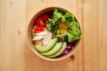 Healthy colorful chicken salad bowl with avocado and fresh vegetables top view