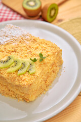 Delicious walnut layer cake with kiwi garnish on white plate