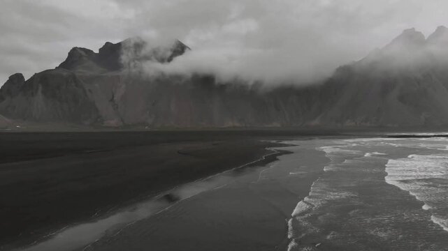 Black sand beach meets the ocean under a cloudy sky