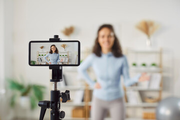 Woman fitness blogger recording video of training or expert tips on smartphone, inspiring you to do...