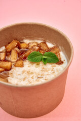 Warm cinnamon apple oatmeal with fresh mint in eco-friendly cup