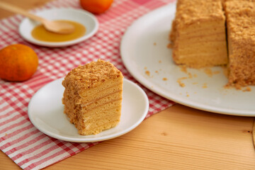 Layered honey cake with crumb topping on red checkered cloth featuring whole mandarin oranges