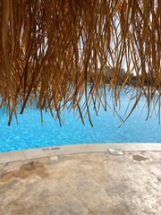 View of the pool from under a luxury umbrella at the hotel pool. Concept of rest, travel, tourism